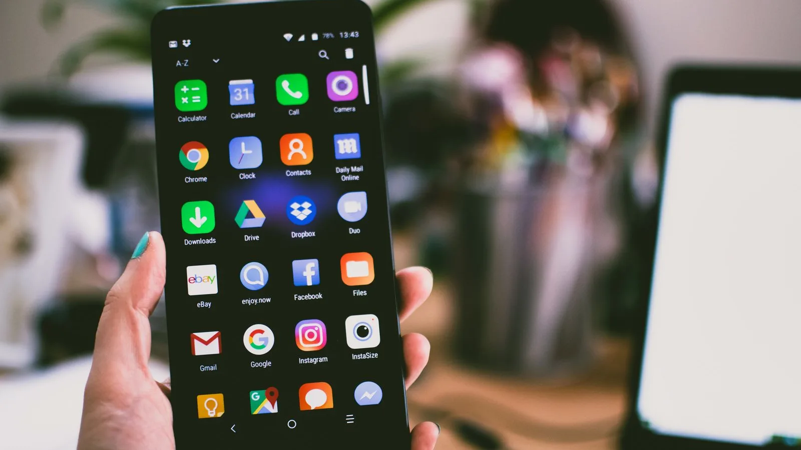 Hand holding a phone full of social media apps — Facebook page versus your own website